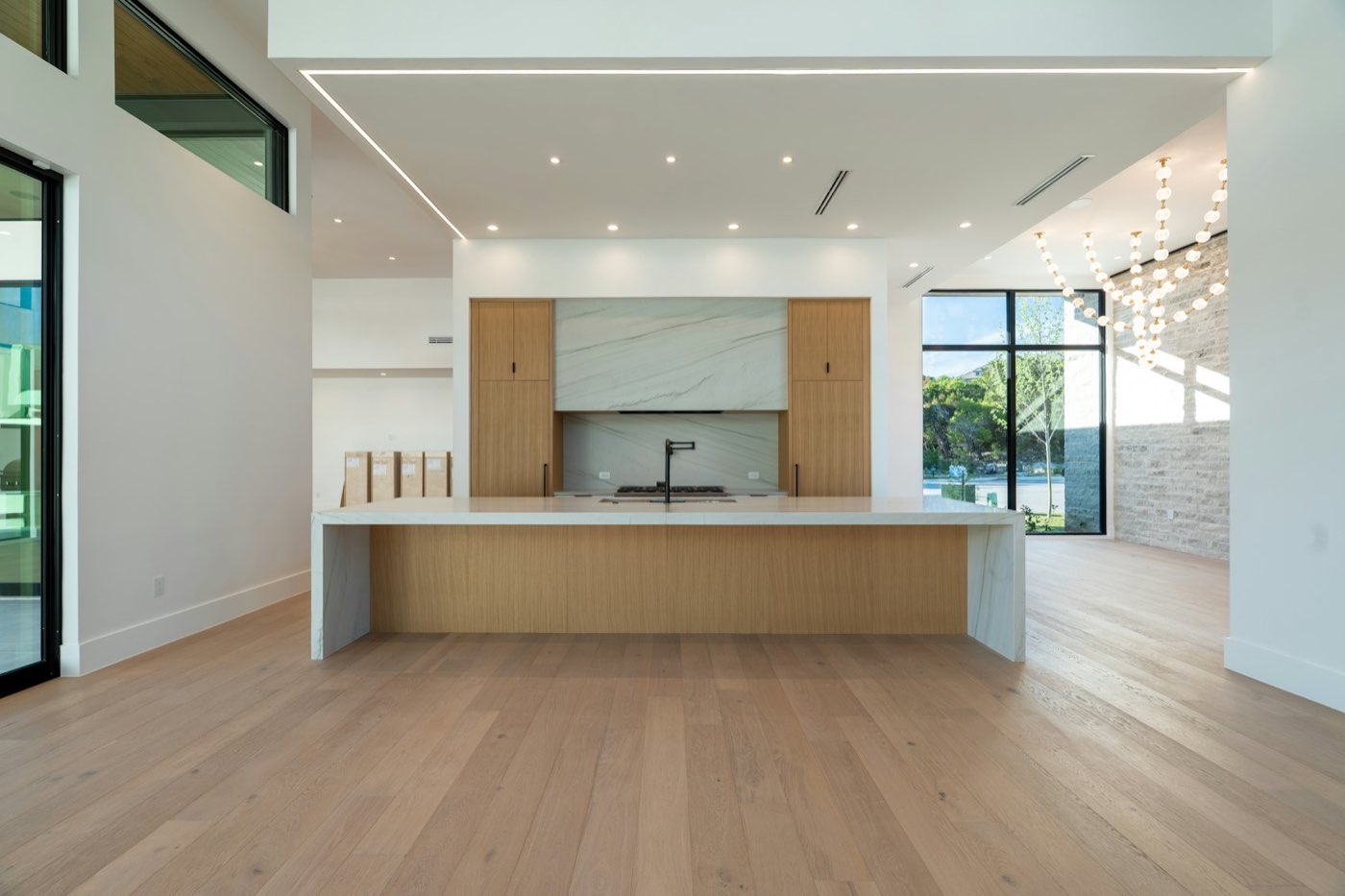 White-oak kitchen island under a marble hood with wide-plank floors